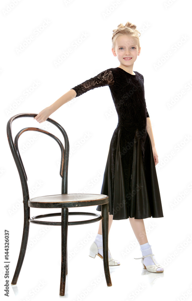 Fototapeta premium Slender little dancer posing near the old Vienna chair.