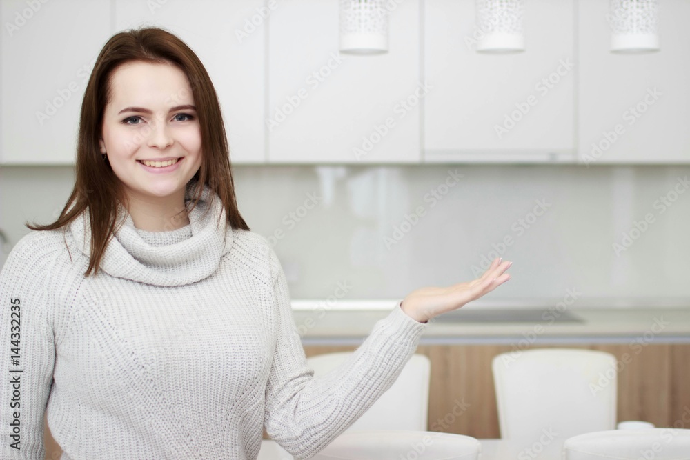 Serious attitude. Young smiling lady standing in a kitchen.