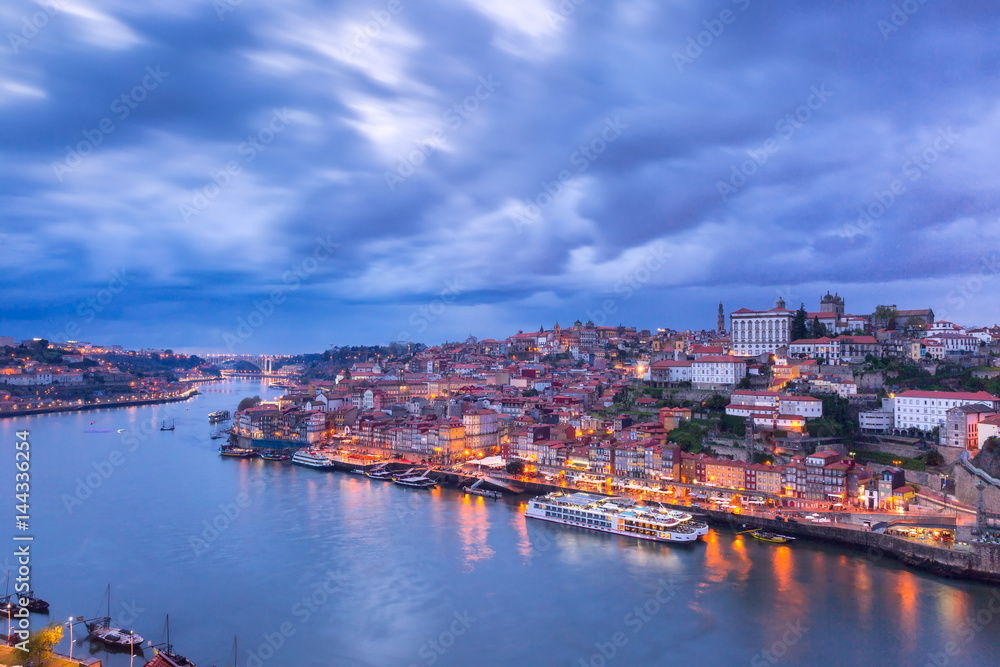 Picturesque panoramic aerial view of Old town of Porto, Ribeira and bridge with mirror reflections in the Douro River during evening blue hour, Portugal