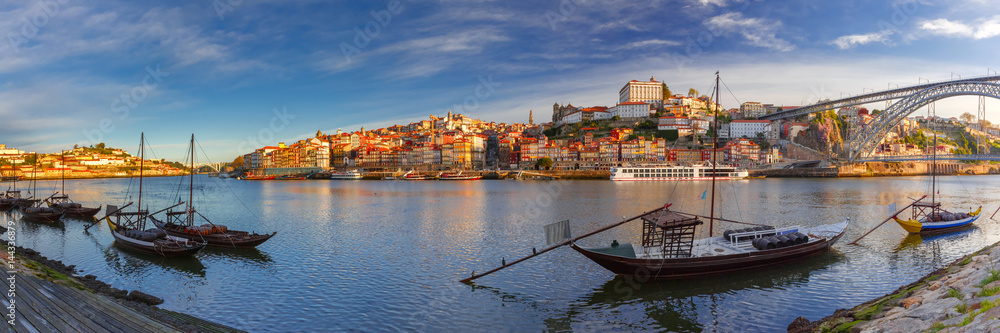 Panoramic view of traditional rabelo boats with barrels of Port wine on the Douro river, Ribeira and Dom Luis I or Luiz I iron bridge on the background, Porto, Portugal.