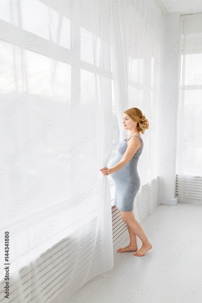 pregnancy, motherhood, people and expectation concept - close up of happy pregnant woman with big belly at window pregnancy, motherhood, people and expectation concept - close up of happy pregnant woman with big belly at window
