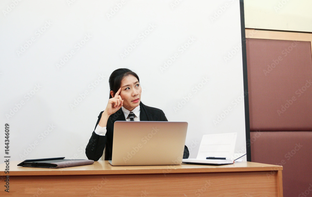 Working woman in black suit wear tie is thinking laptop in front of her white background Working woman in black suit wear tie is thinking laptop in front of her white background