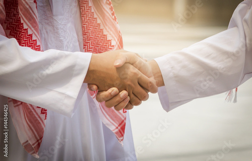 Obraz na płótnie Arab and businessman are shaking hand on cityscape background, Business Successful concept, w salonie