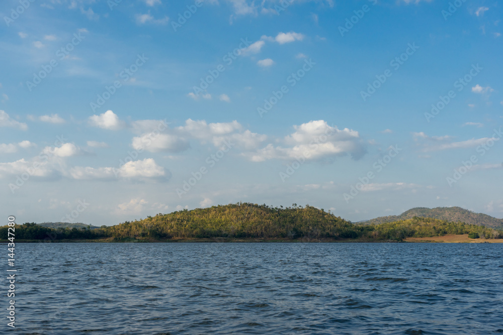 Blue background of water and sky with yellow forest