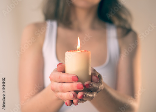 Woman hands holding burning candle light blur background