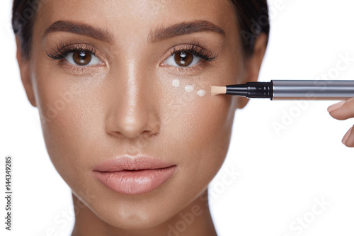 Beauty Woman Face Makeup. Female Applying Corrector Under Eyes photo