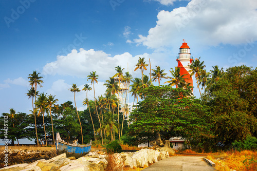 Thangassery Lighthouse on the cliff surrounded by palm trees and big sea waves on the Kollam beach. Kerala, India photo