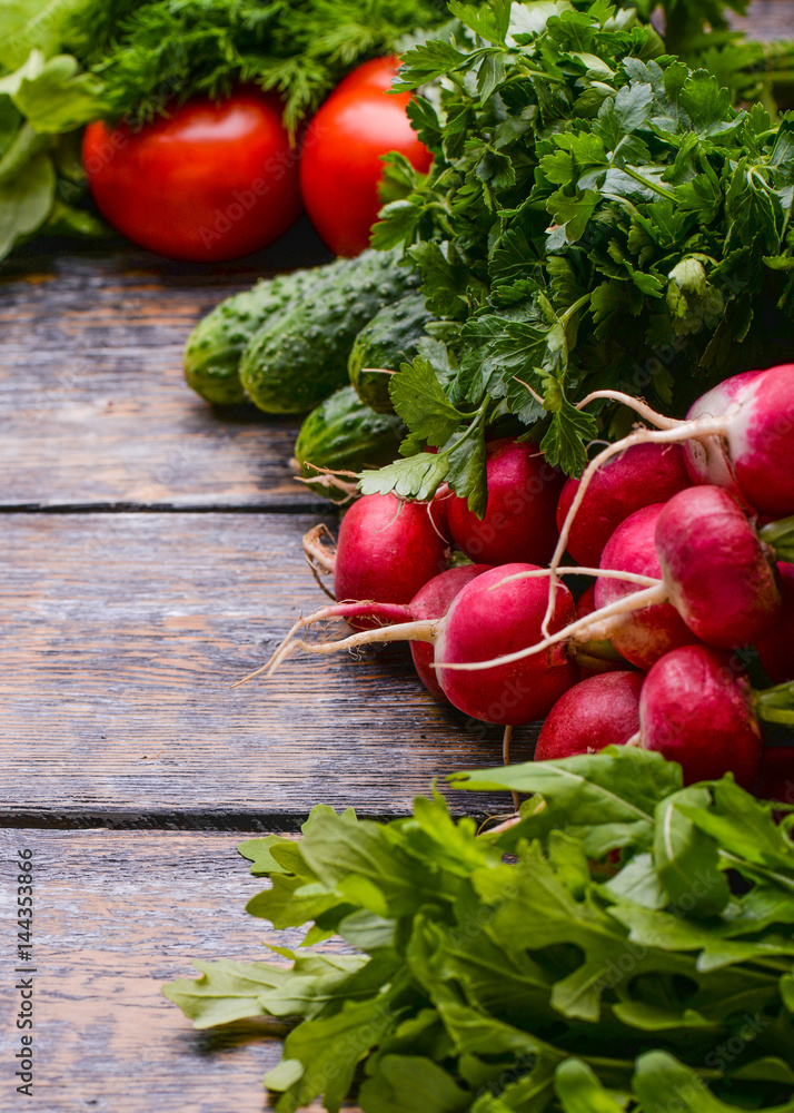 Harvest Vegetables: sadishes, tomatoes, cucumbers, parsley, onion, arugula at the basket on the wooden background Harvest Vegetables: sadishes, tomatoes, cucumbers, parsley, onion, arugula at the basket on the wooden background