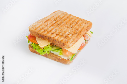 Close up sandwich with salmon, fresh tomatoes and cucumber, cheese and lettuce with toasted bread. Isolated on the white background, selective focus
