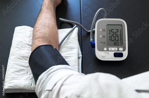 Hypertensive patient performing a blood pressure auto test / man self-monitoring of blood pressure with a tensiometer 