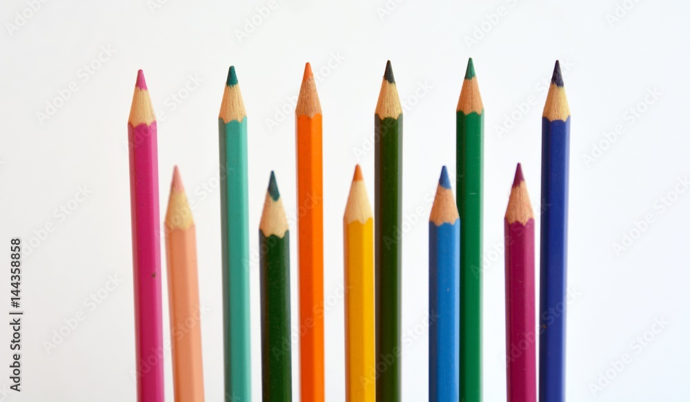 Colored pencils in a row in front of a white background Colored pencils in a row in front of a white background