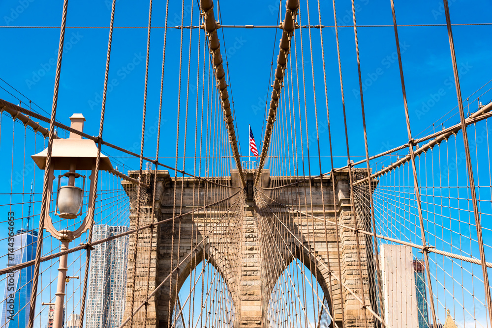 Fototapeta premium american flag flying on an arch of Brooklyn Bridge, New York