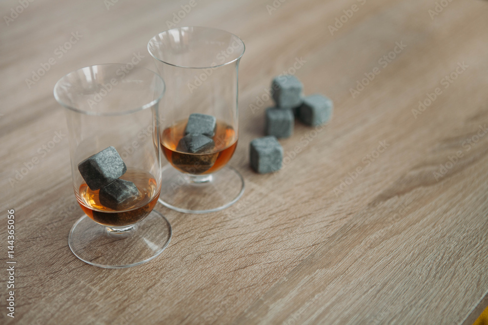 Stones for cooling whiskey and glases tulup on light wooden background Stones for cooling whiskey and glases tulup on light wooden background
