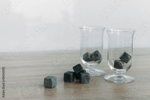 Stones for cooling whiskey and glases tulup on light wooden background photo
