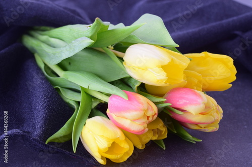 Bouquet of multicolored tulips on a grey cloth. Spring flowers. Romance. photo