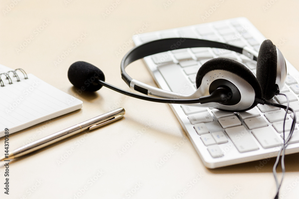 Office desk with headset and keyboard brown background Office desk with headset and keyboard brown background