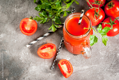 Tomato juice in mason jar, with tomatoes and greens On a gray concrete table. 