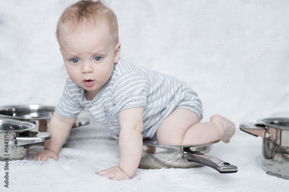 Mother's helper in a set of cooking pots and pans. Infant boy playing ...