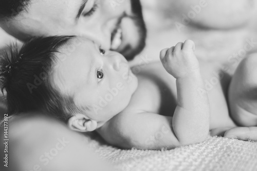 Father and newborn baby closeup. Father and newborn lying on the bed. A man is hugging a child. black and white photo