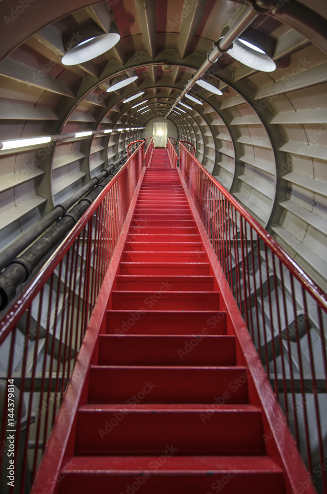 Fototapeta premium Red staircase in a round metal tunnel