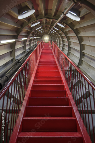Red staircase in a round metal tunnel