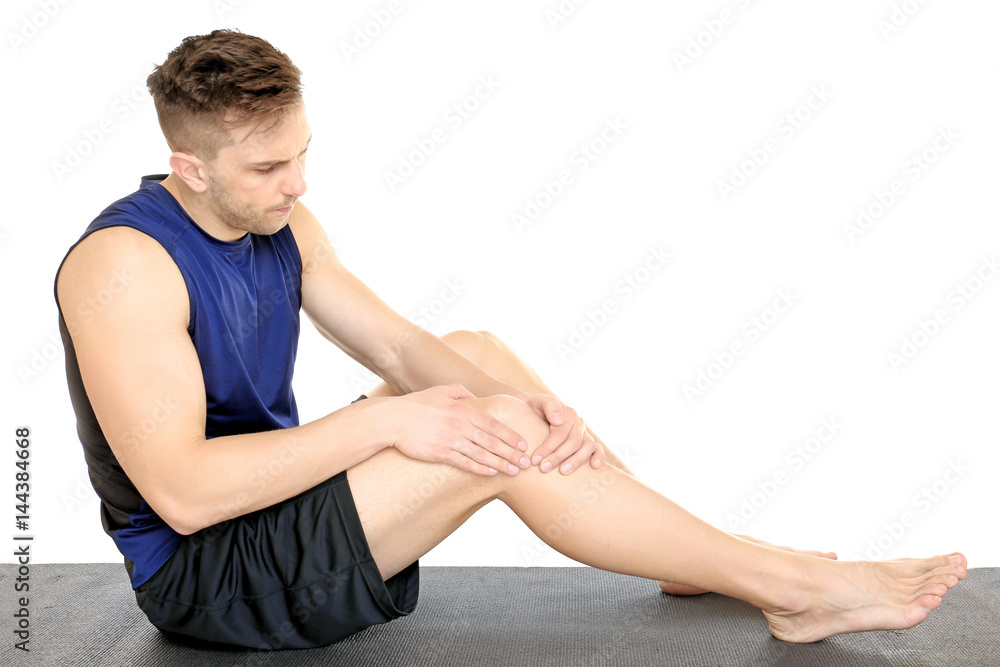Sporty young man suffering from pain in leg on white background Sporty young man suffering from pain in leg on white background