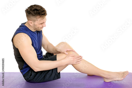Sporty young man suffering from pain in leg on white background