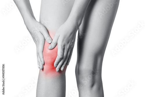 Closeup view of a young woman with knee pain. isolated on white background. Black and white photo with red dot. photo