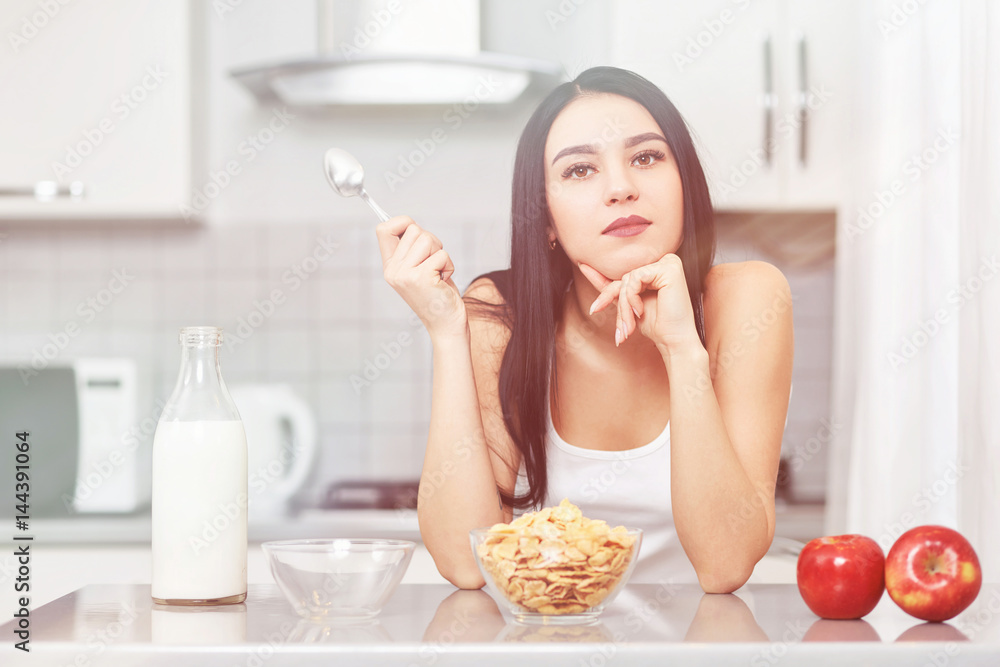 Young woman in white clothes sitting in the kitchen Young woman in white clothes sitting in the kitchen