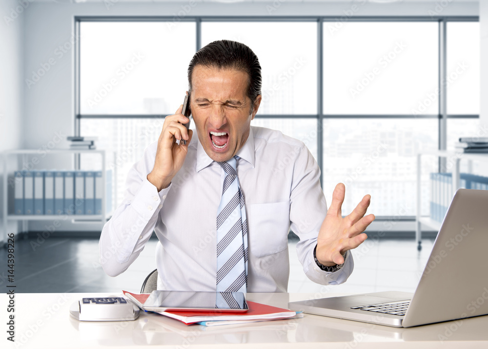 angry senior businessman in stress working and talking on mobile phone at computer desk angry senior businessman in stress working and talking on mobile phone at computer desk
