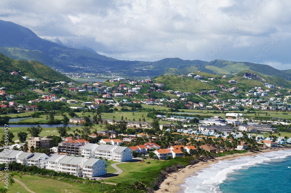 A view over St. Kitts Island with residential area on the foreground and lush green hills on the background A view over St. Kitts Island with residential area on the foreground and lush green hills on the background