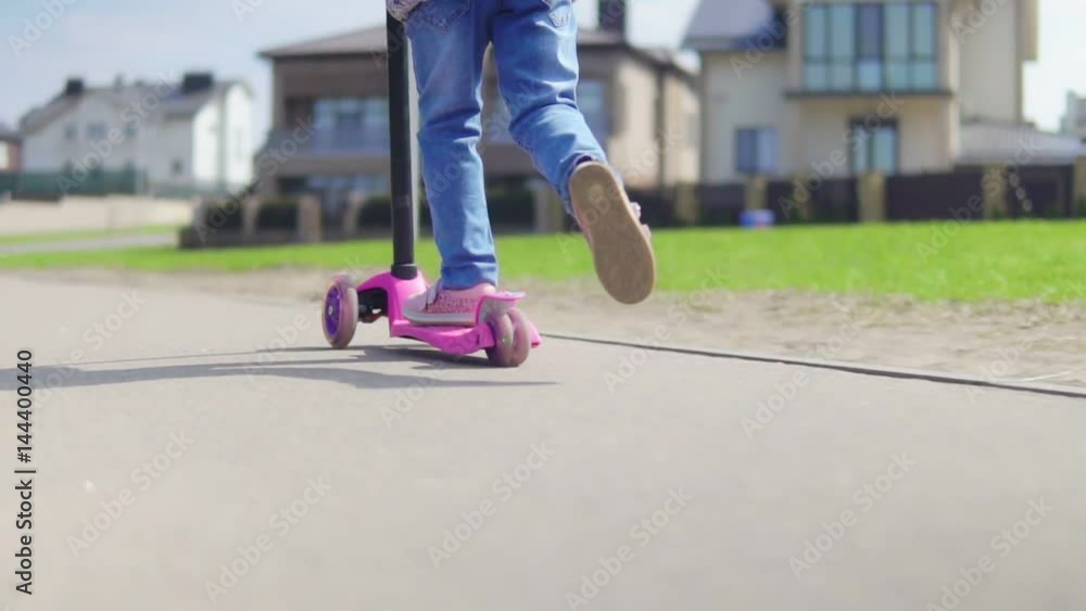 A child is riding a scooter on a sunny day. Slow motion A child is riding a scooter on a sunny day. Slow motion