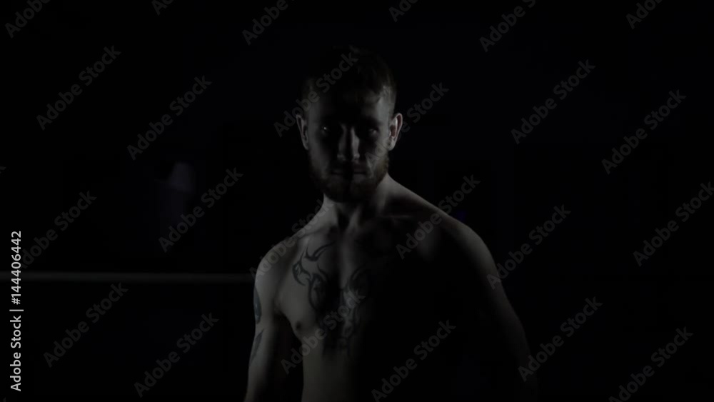 A boxer man stands in a fighting posture in the dark A boxer man stands in a fighting posture in the dark