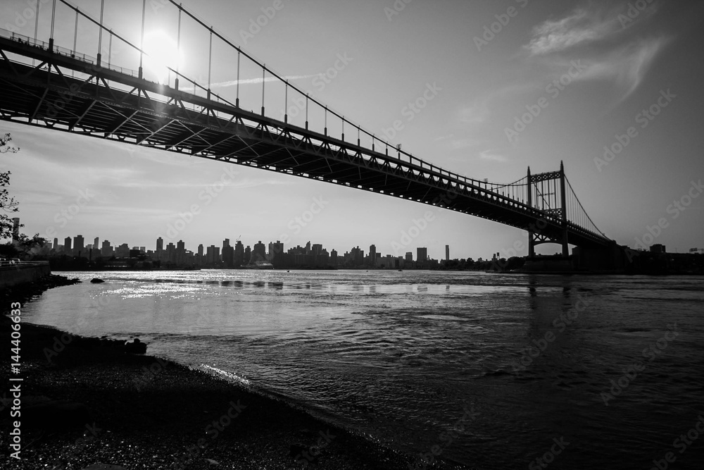 Triborough bridge over the river and dark shore in black and white style, New York