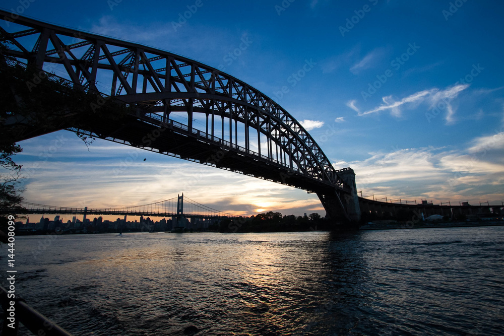 Silhouette of Hell Gate Bridge and Triborough bridge over the river, New York