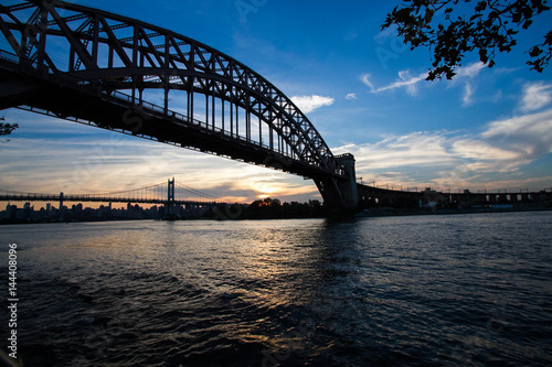 Fototapeta Naklejka Na Ścianę i Meble -  Silhouette of Hell Gate Bridge and Triborough bridge over the river, New York