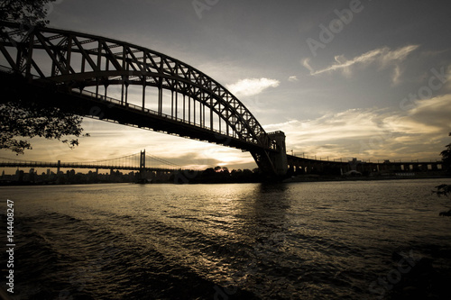 Dark Silhouette of Hell Gate Bridge and Triborough bridge over the river in vintage style, New York © Spinel
