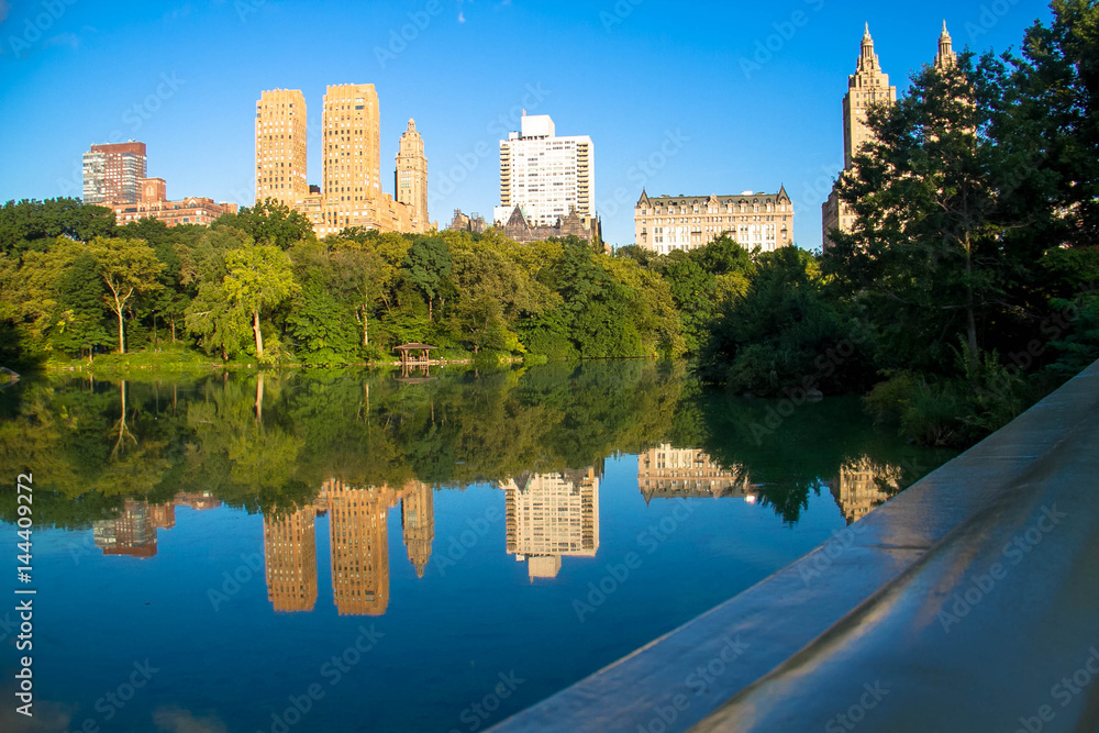 Reflection of buildings in the lake at Central Park with blue sky