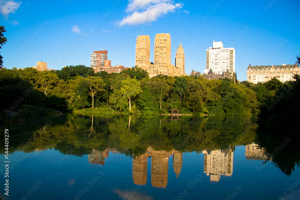 Reflection of buildings in the lake at Central Park with blue sky, New York Reflection of buildings in the lake at Central Park with blue sky, New York