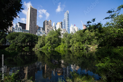 Reflective lake under the shade and buildings of Manhattan in summer