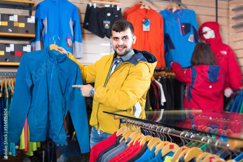 Couple examining track jackets in sports clothes store
