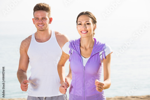 Happy young couple running on beach by sea
