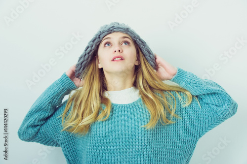 Pretty young girl with blond hair in fashionable sweater, hat