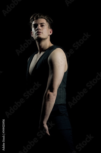 Handsome man posing in unbutton vest with muscular torso