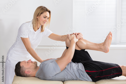 Physiotherapist Giving Knee Exercise To A Man