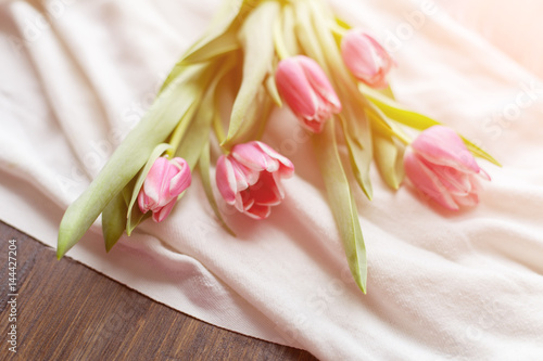 Pink tulips on white fabric, lit by the rays of the setting sun