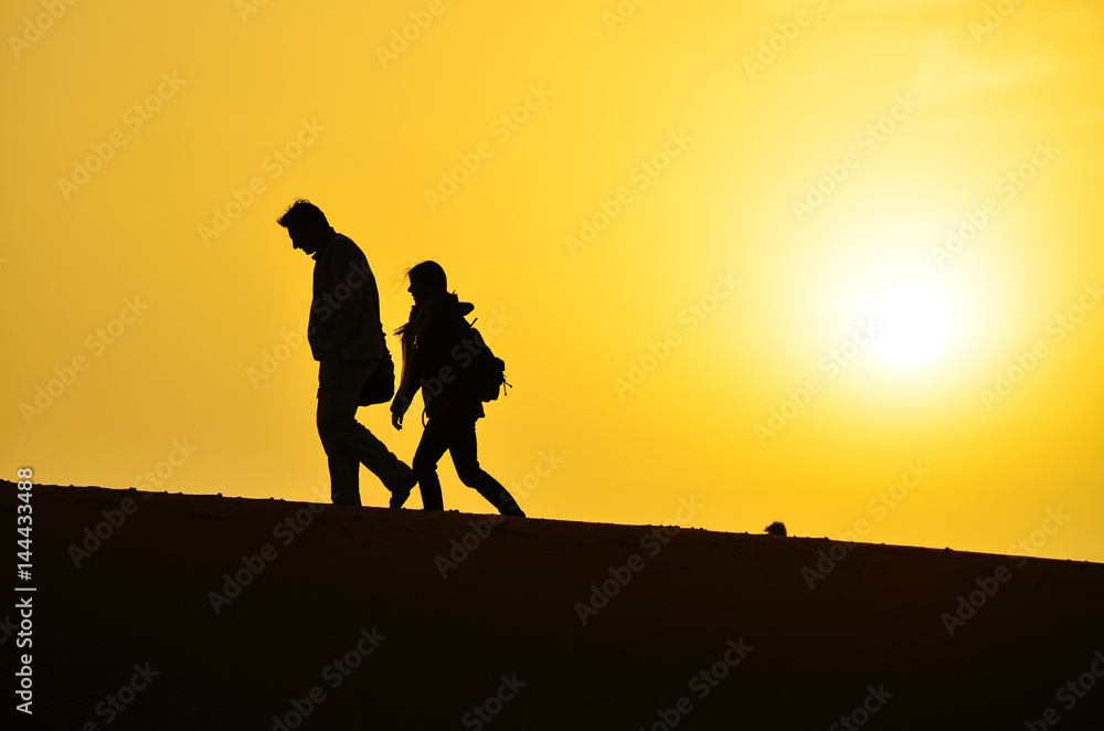 Silhouette of a Man and a Woman Walking on the Sand Dunes of the Sahara Desert During Sunrise