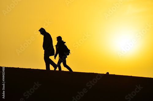 Silhouette of a Man and a Woman Walking on the Sand Dunes of the Sahara Desert During Sunrise