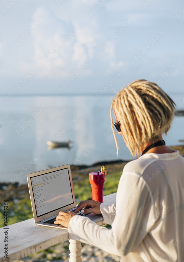 Woman working on laptop in beach bar