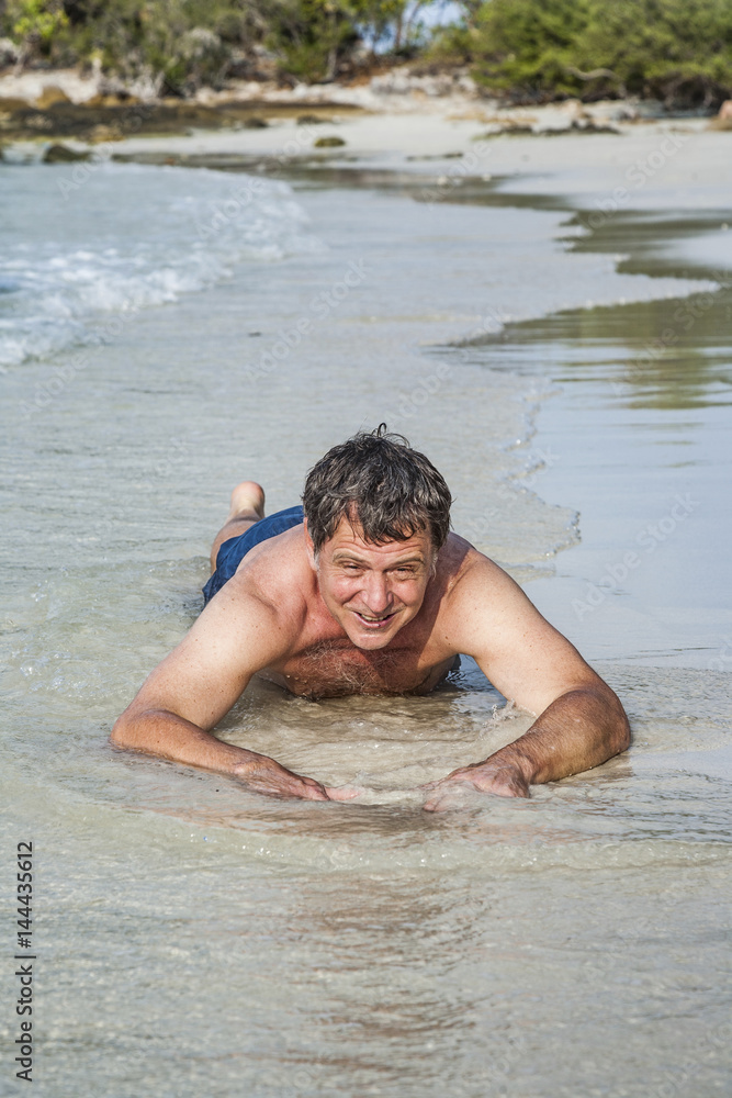 man in bathingsuit is lying at the beach